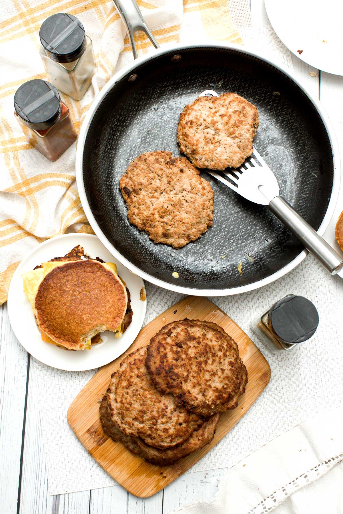 A stack of turkey breakfast patties on a board next to a breakfast sandwich cooked in a Hexclad Hybrid Pan.