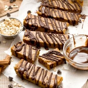 Gluten-free chocolate pumpkin protein bars with chocolate drizzle on top and oat flour.