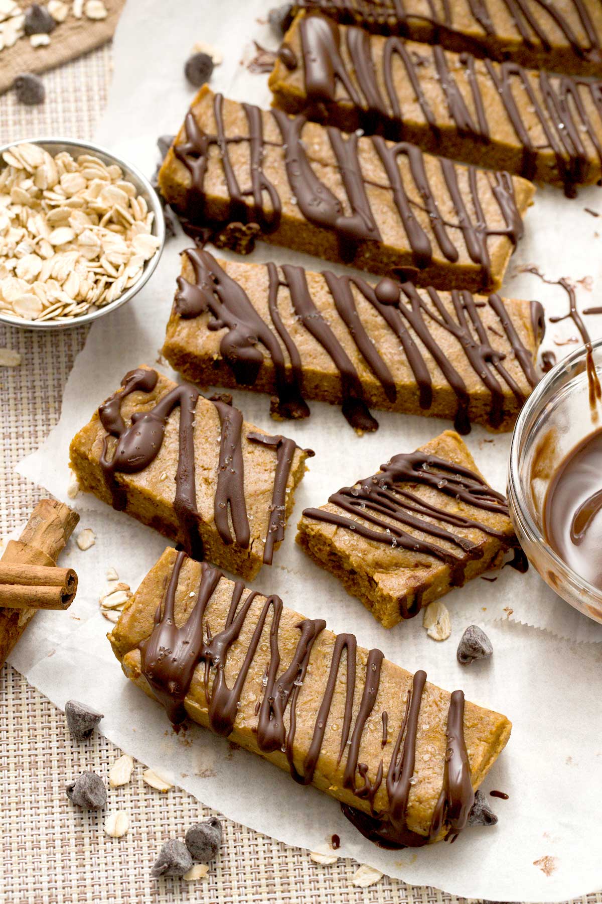 A close-up of gluten-free chocolate pumpkin protein bars with chocolate drizzle on top and oat flour.