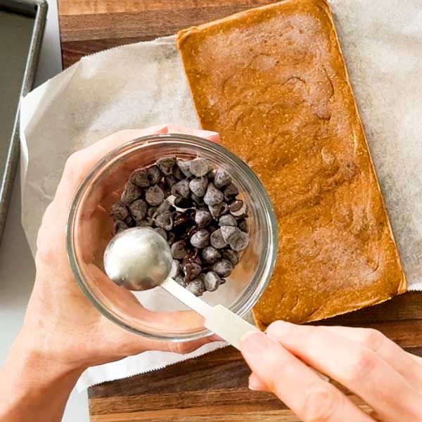 Adding the coconut oil to the chocolate chips in a glass bowl.