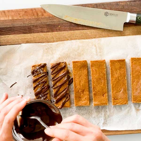 Drizzling chocolate on top of the protein bars.