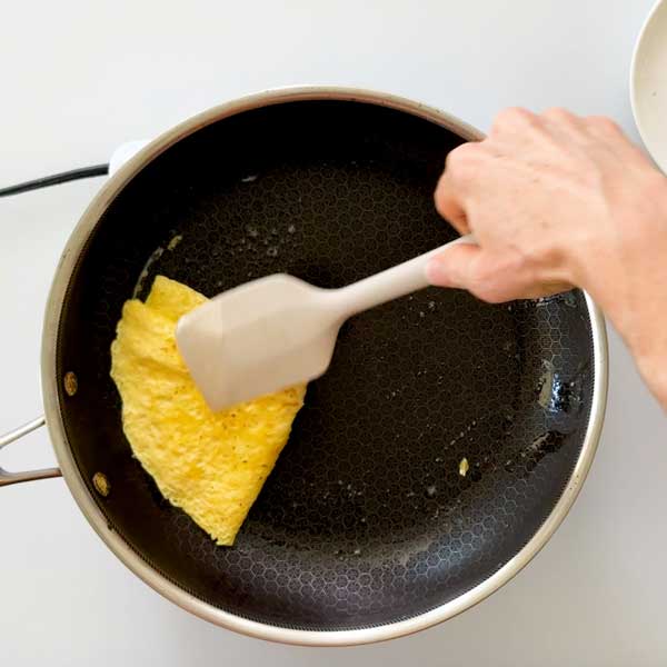 Folding the egg omelet in the skillet with a spatula.