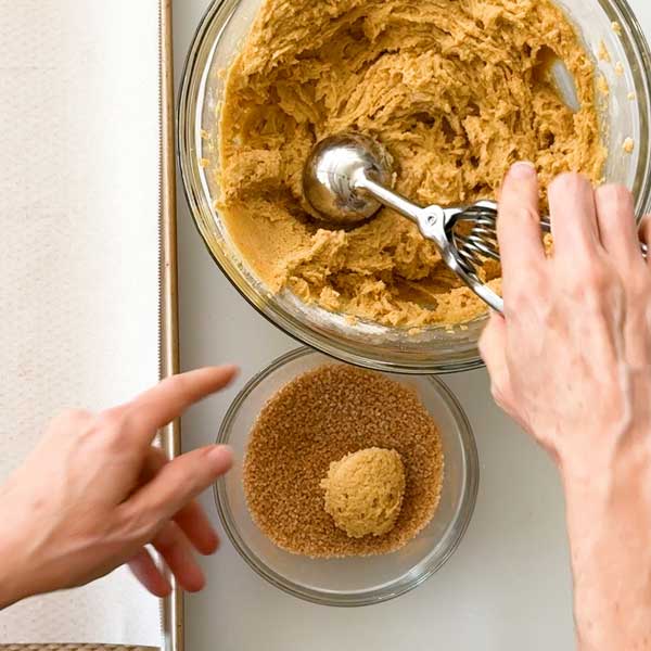 Scooping the cookie dough in to the cinnamon sugar mixture.