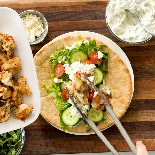 Assembling the chicken gyro with fresh vegetables and chicken.