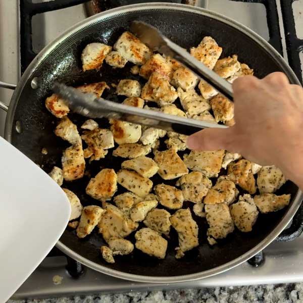 Removing the seared chicken from the pan and onto a plate to rest.