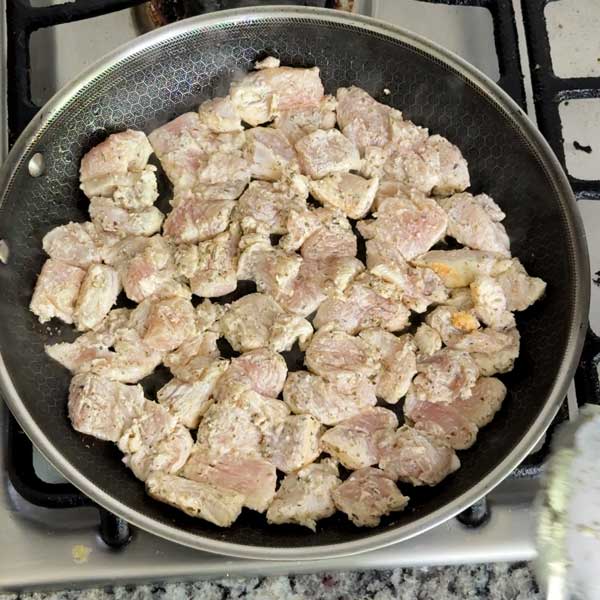 Browning the marinated chicken breast pieces in a skillet.