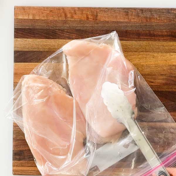 Removing the pounded chicken breasts from a bag.