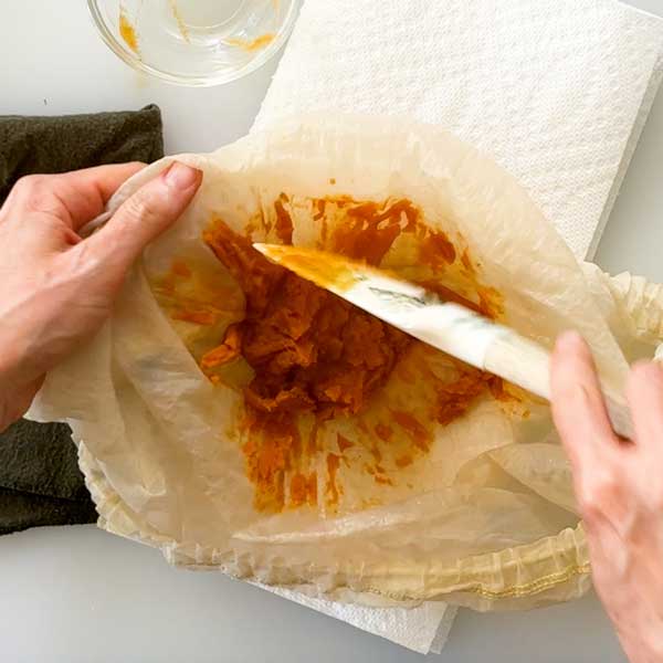Scraping the pumpkin paste out of the strainer bag.