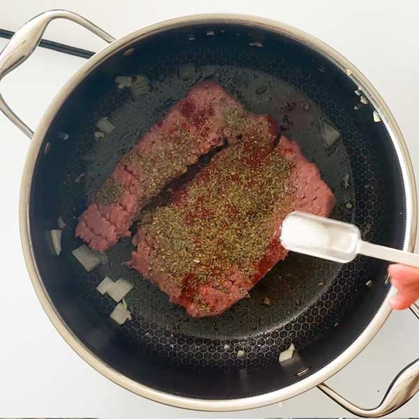 Adding the sausage seasonings to the ground turkey in the pot.