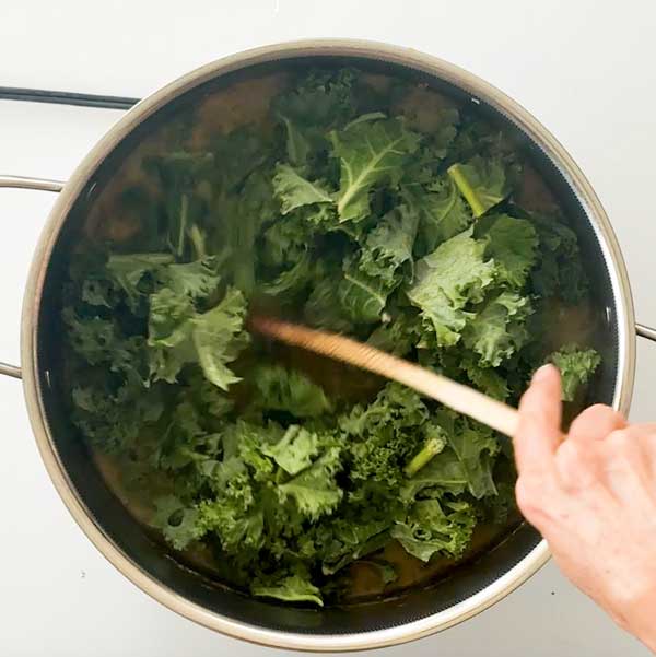 Stirring the kale into the soup.