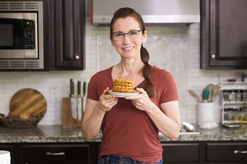 Nicole holding pumpkin waffles in her kitchen.