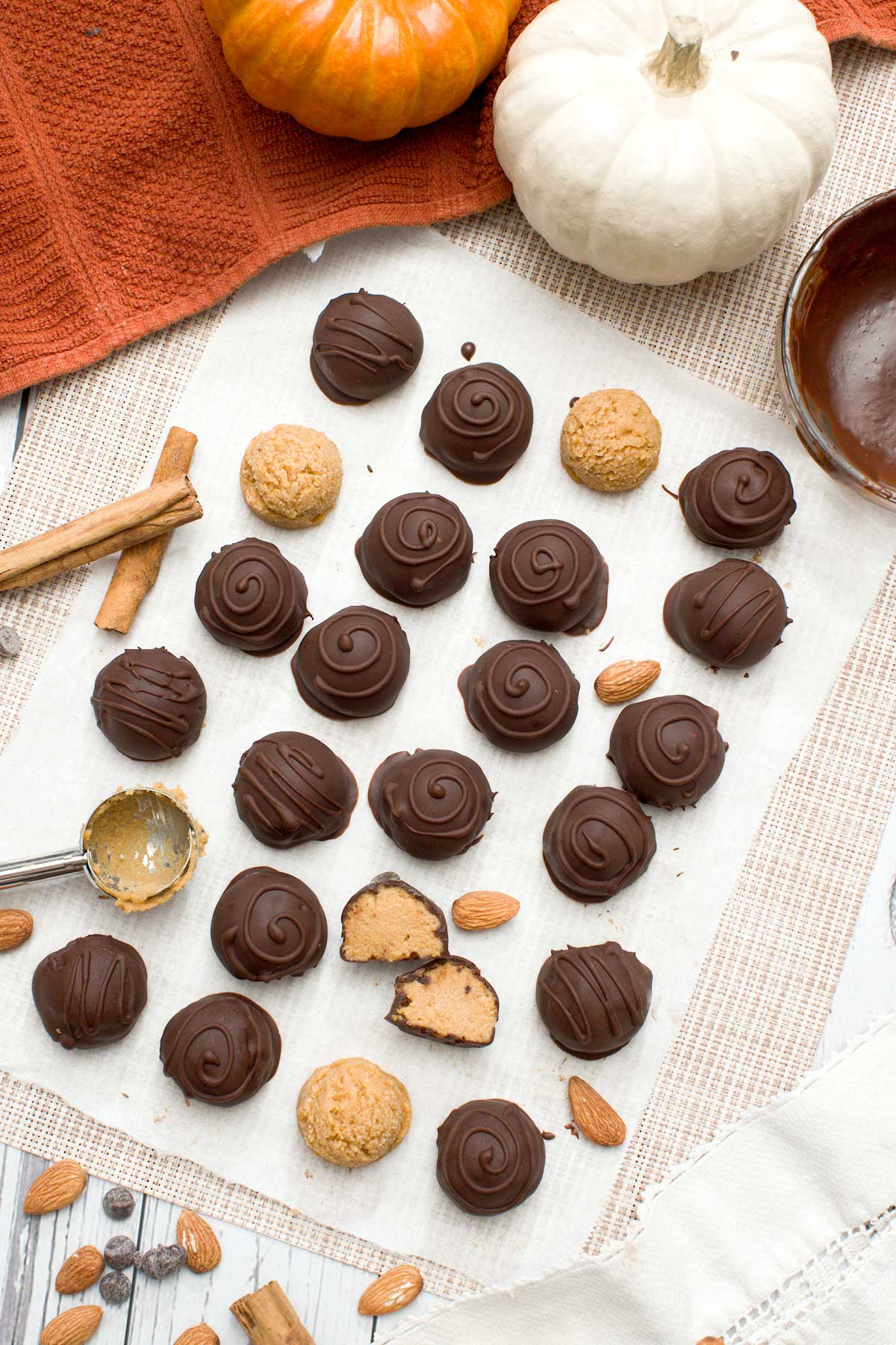 The top view of a batch of chocolate pumpkin truffles dipped in chocolate with swirls on top.