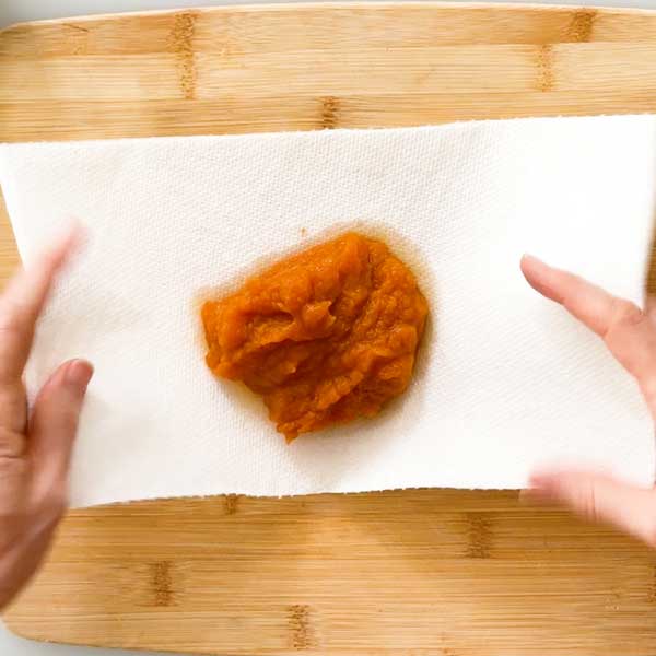 Putting the pumpkin puree in the center of three layers of paper towels.