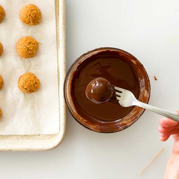 Dipping the truffle in melted chocolate.