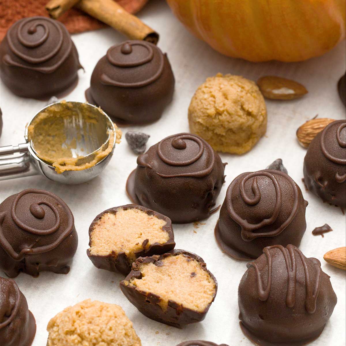 Chocolate pumpkin truffles dipped in chocolate with swirls on top.