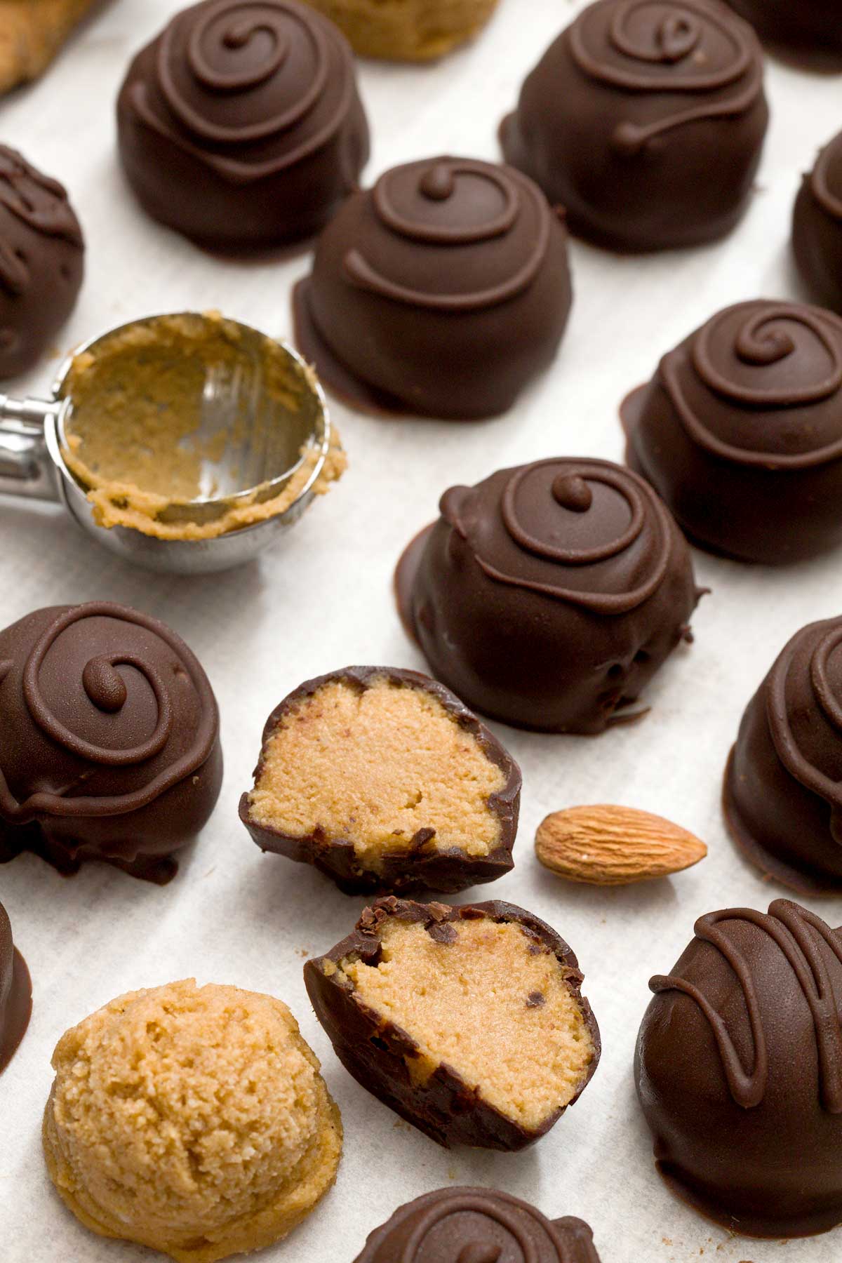 A batch of chocolate pumpkin truffles dipped in chocolate with swirls on top.