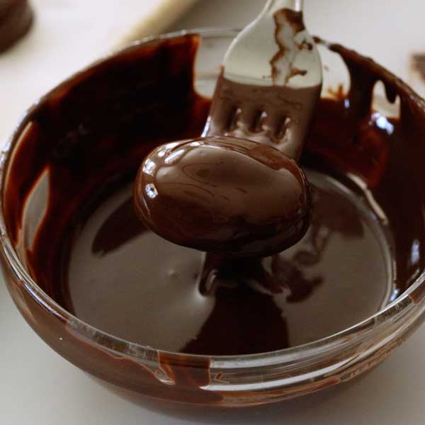Dipping the chilled bar in the melted chocolate.
