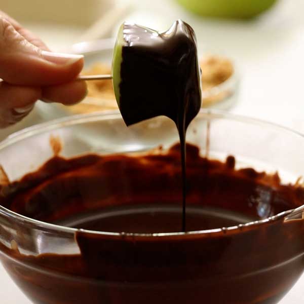 Dipping the apple bite in the melted chocolate.