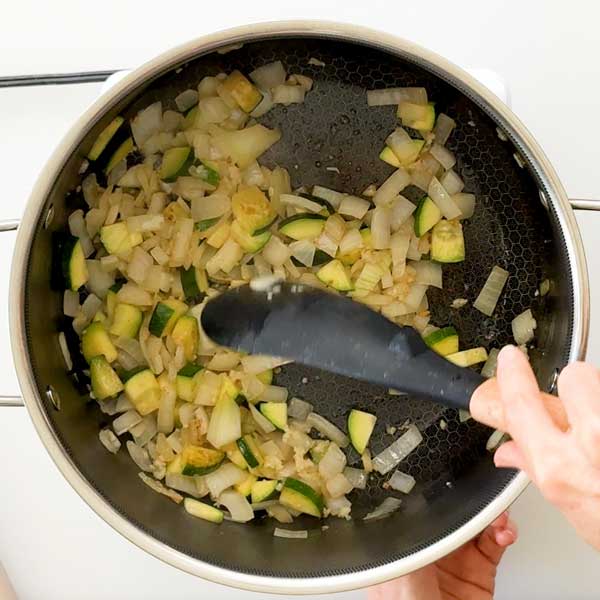 Sauteeing the onions, zucchini and garlic until soft in the pot.