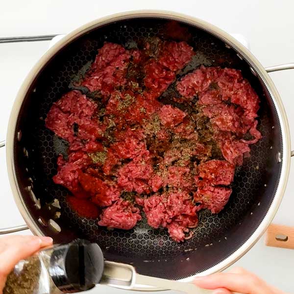 Sprinkling the seasonings over the ground beef.