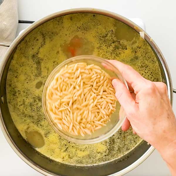 Adding the orzo to the soup.