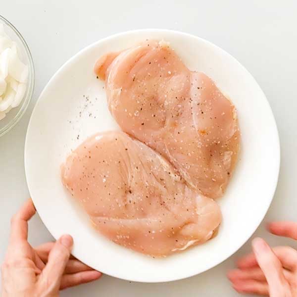 Seasoning the pounded chicken breasts with salt and pepper.