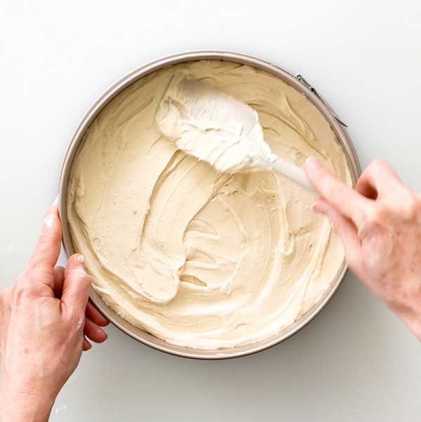 Spreading the cheesecake filling over the pressed crust.