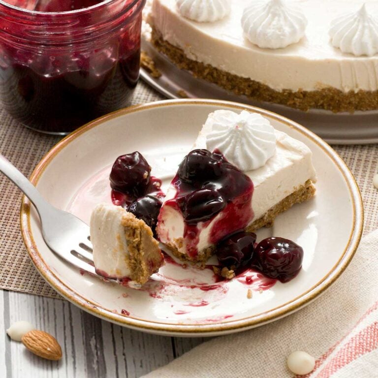 A slice of no-bake cottage cheese cheesecake with a gluten-free crust and cherry sauce on top.