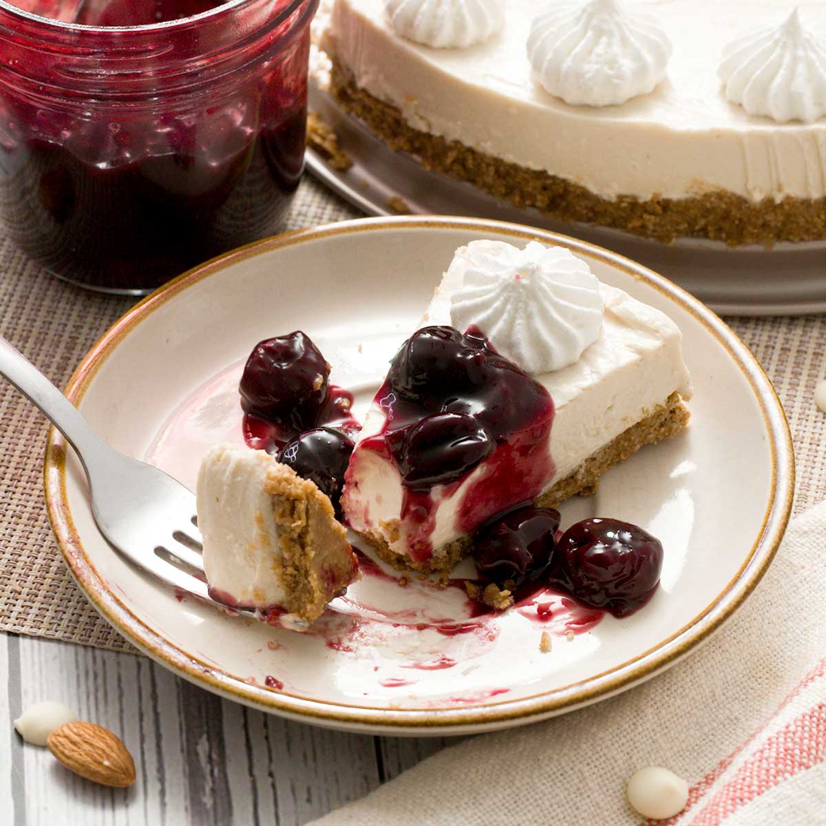 A slice of no-bake cottage cheese cheesecake with a gluten-free crust and cherry sauce on top.