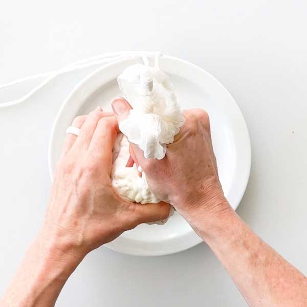 Straining excess liquid from the cottage cheese.
