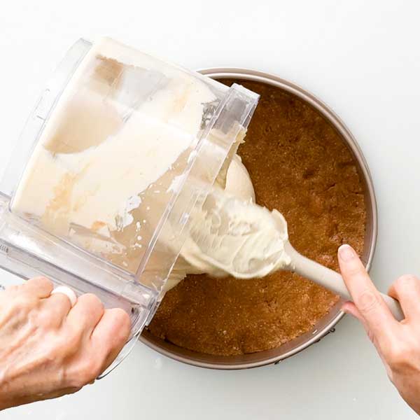 Dumping the cheesecake filling on top of the crust.