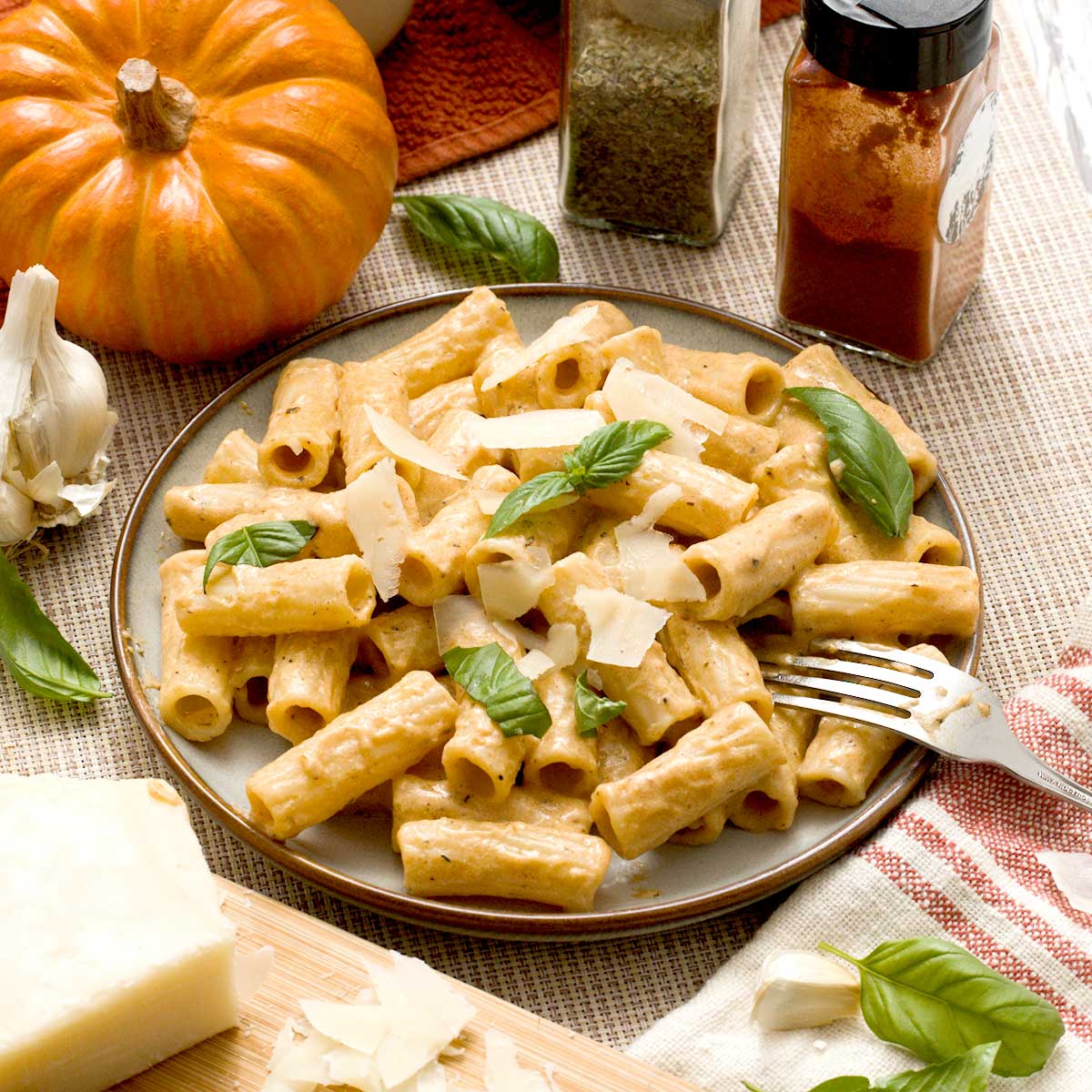 A plate of protein pumpkin pasta sauce with cottage cheese. on rotini pasta with parmesan cheese on top.
