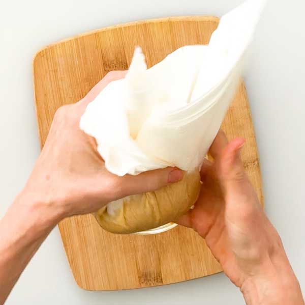 Gently squeezing the extra moisture out of the pumpkin puree.