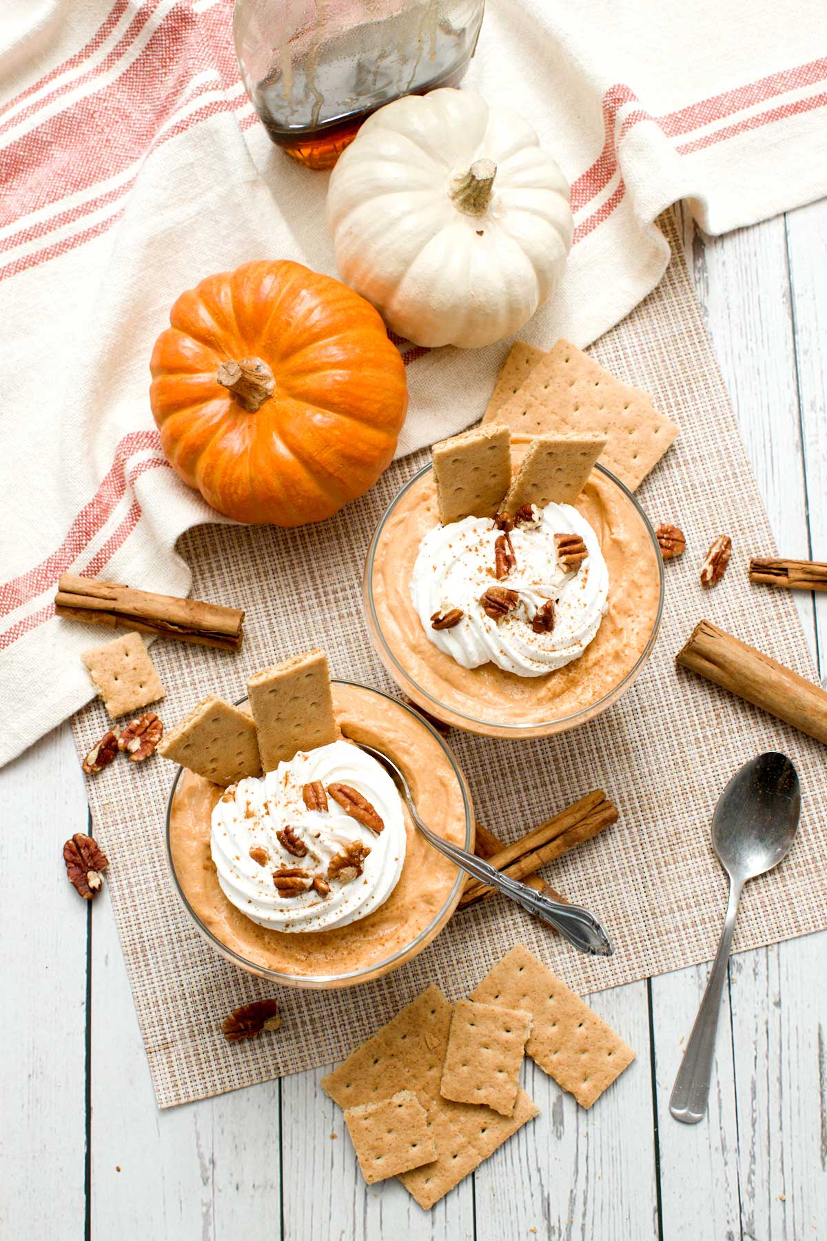 Top view of two bowls of protein pumpkin pudding with cottage cheese and whipped cream on top.