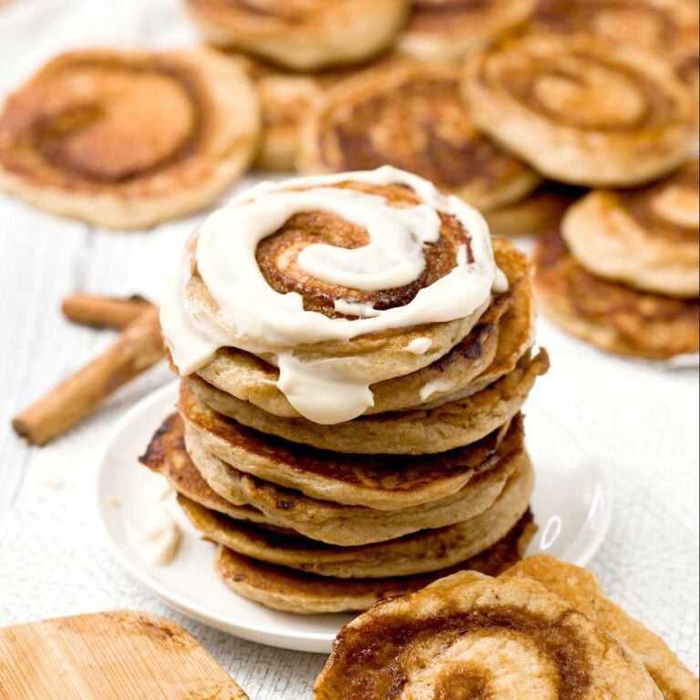 A stack of gluten-free cinnamon roll cottage cheese pancakes with cream cheese on top.