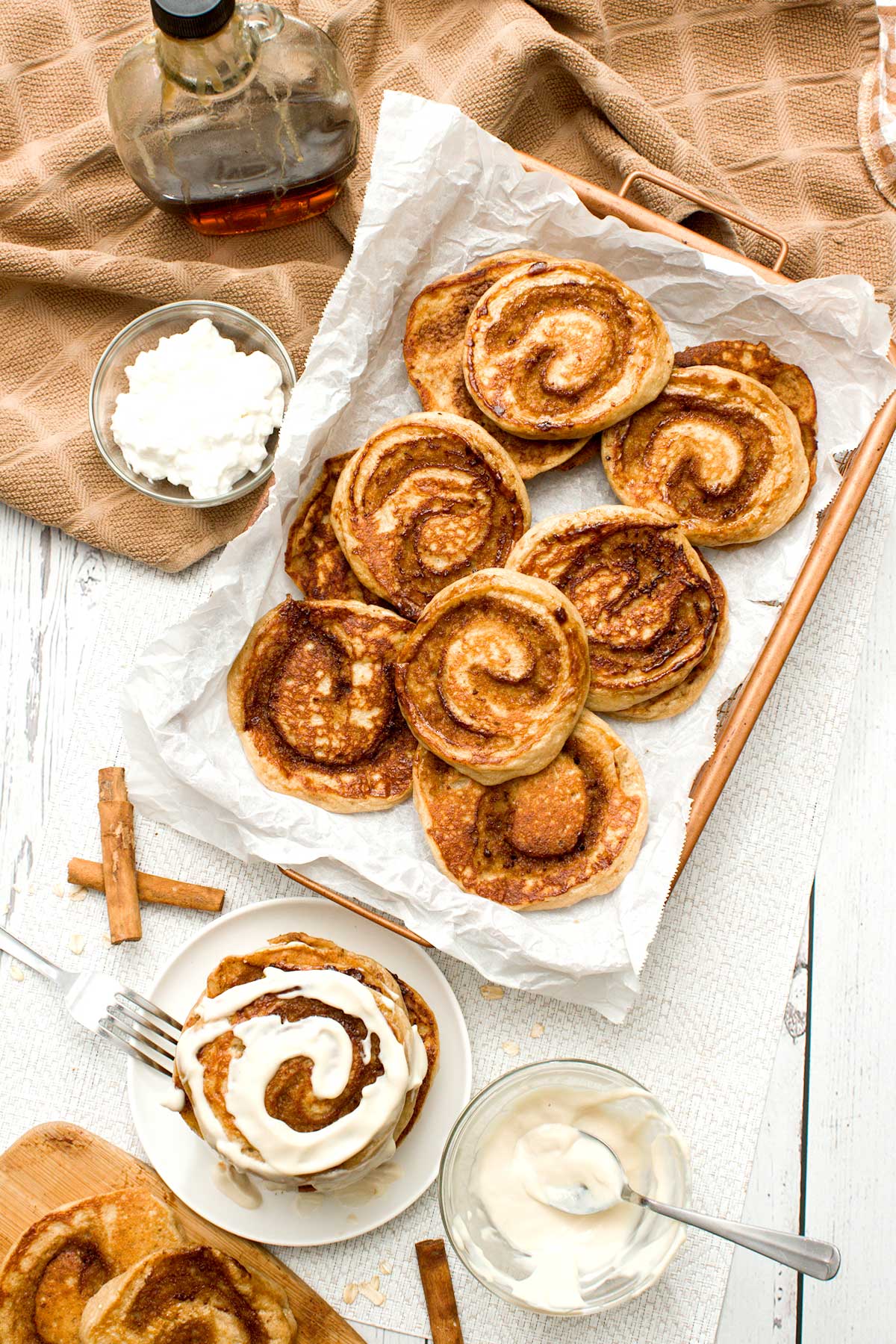 The top of a stack of cinnamon roll cottage cheese pancakes with cream cheese on top.