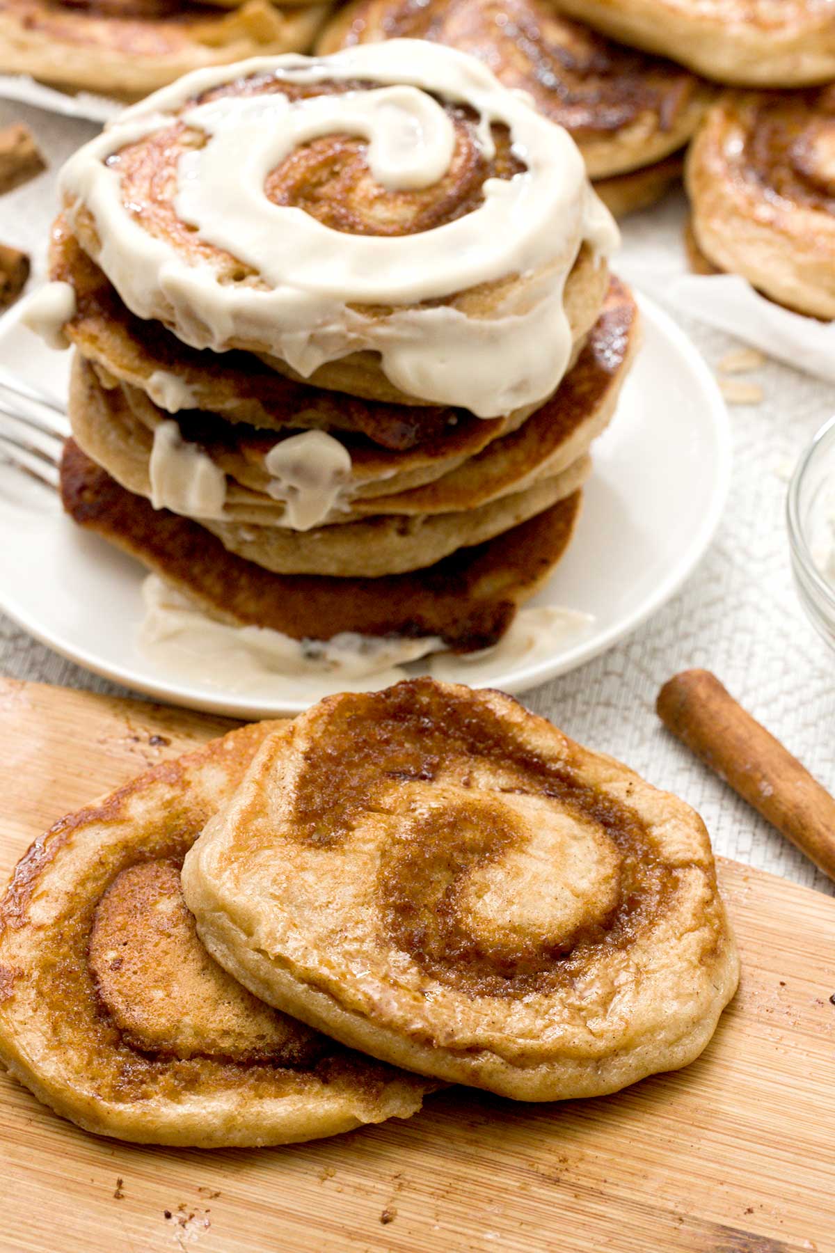 A stack of cinnamon roll cottage cheese pancakes with cream cheese on top.