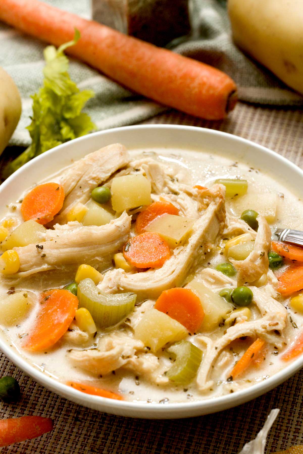 Close-up of a bowl of gluten-free healthy chicken pot pie soup with potatoes, carrots, pan-seared chicken and greek yogurt.