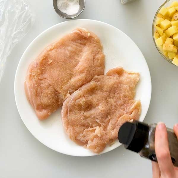 Seasoning the chicken breasts with salt, garlic powder and pepper.