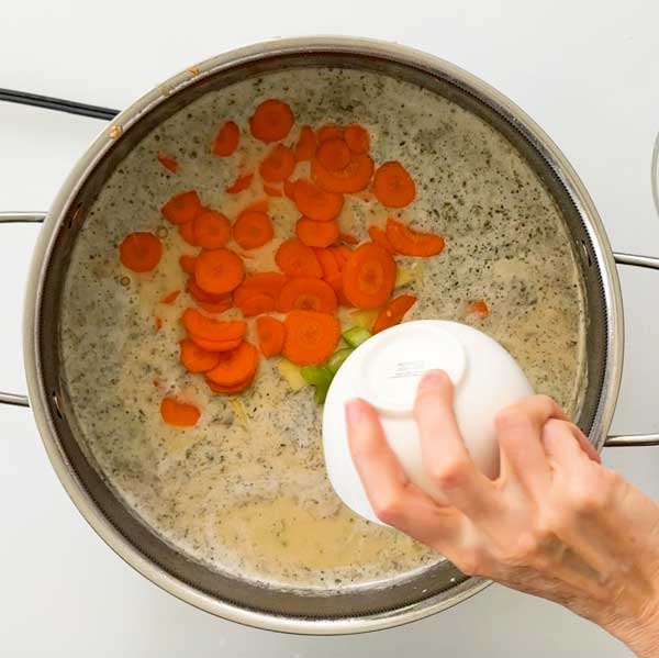 Adding carrots, celery and potatoes to the soup.