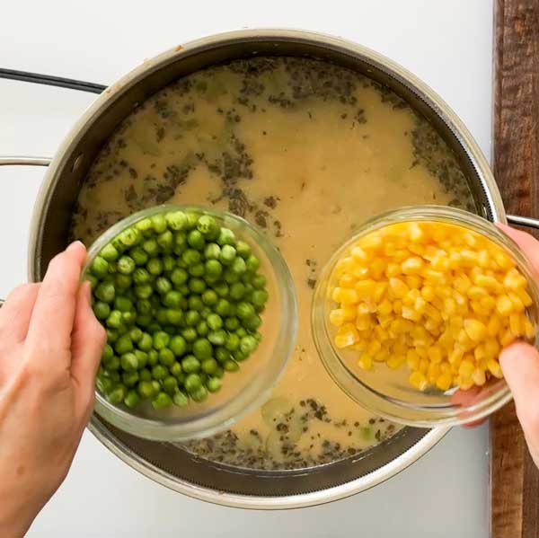 Adding peas and corn to the soup.