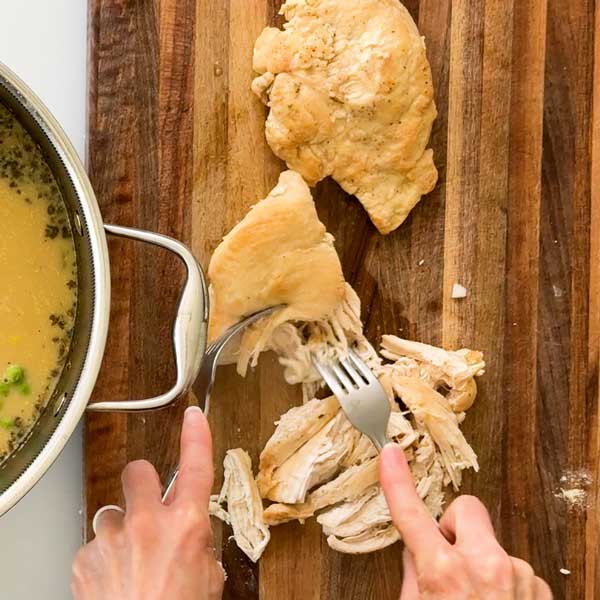 Shredding the chicken with two forks.