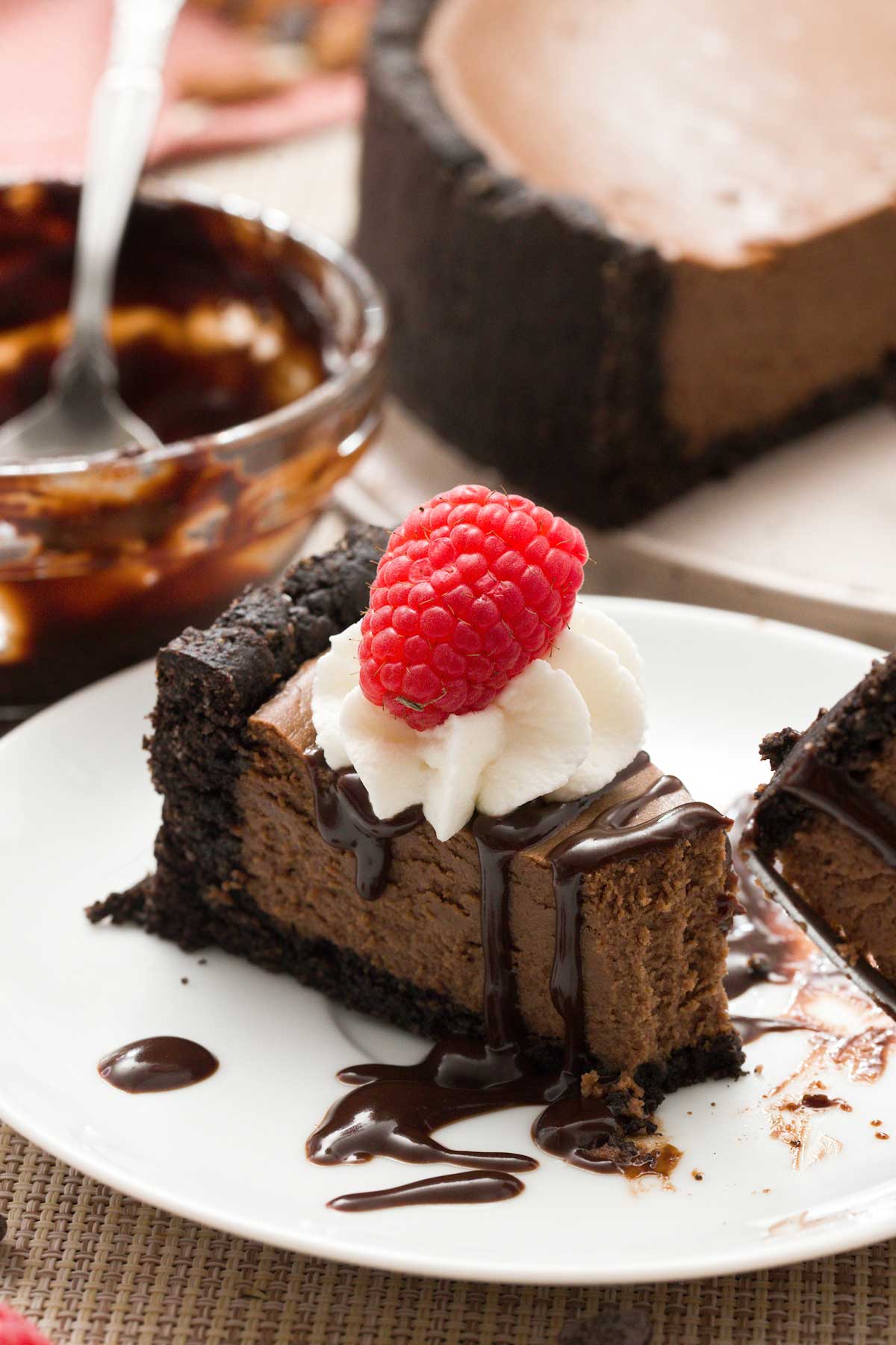 Close-up of a slice of chocolate cheesecake with cottage cheese and protein powder with a raspberry and whipped cream on top.