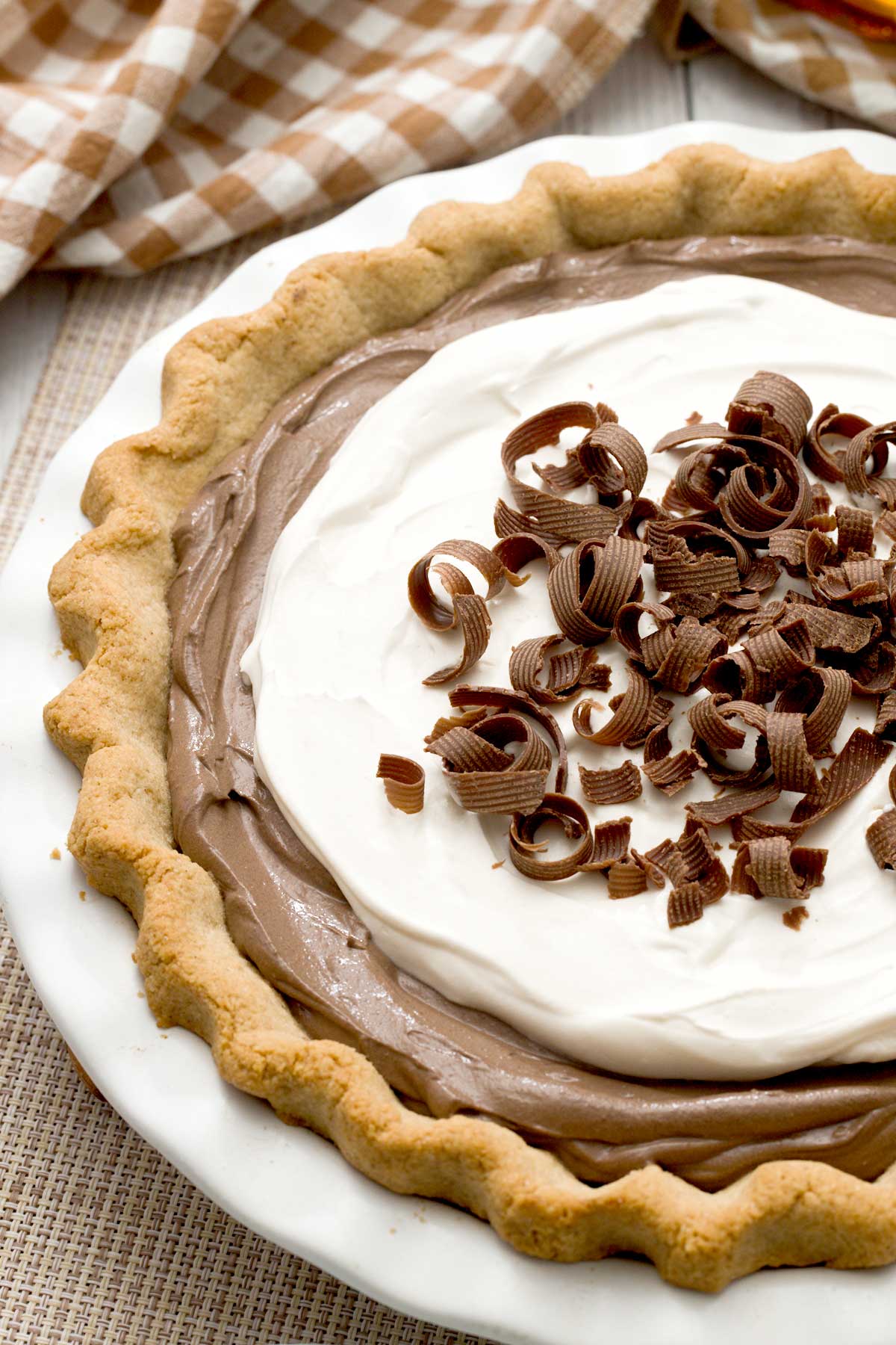 A gluten-free chocolate pie with an almond flour crust and chocolate cottage cheese filling and chocolate curls on top.