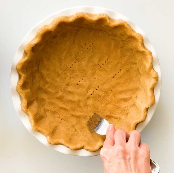 Poking hole in the pie crust with a fork.