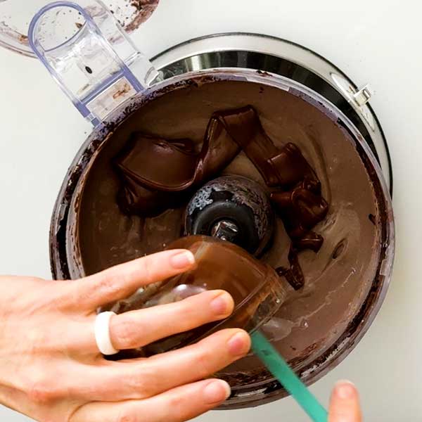 Adding melted chocolate chips to the pie filling in the food processor.