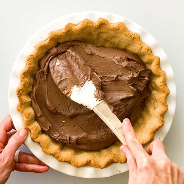 Spreading the chocolate pie filling in the pie crust.