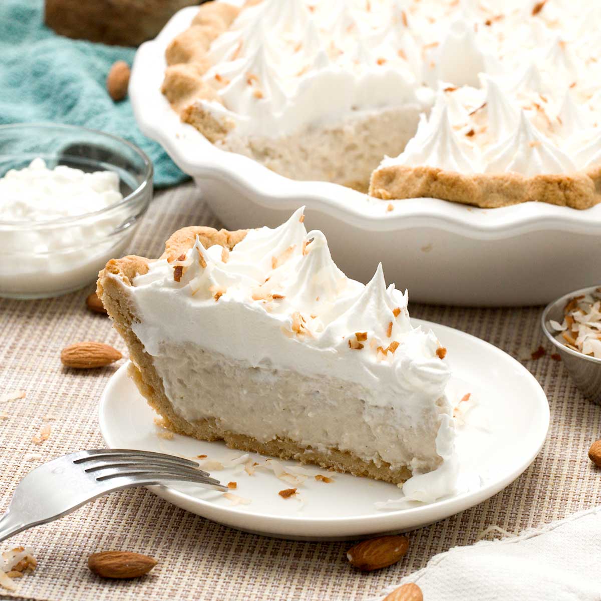 A slice of gluten-free coconut cream pie with an almond flour pie crust and toasted coconut on top.
