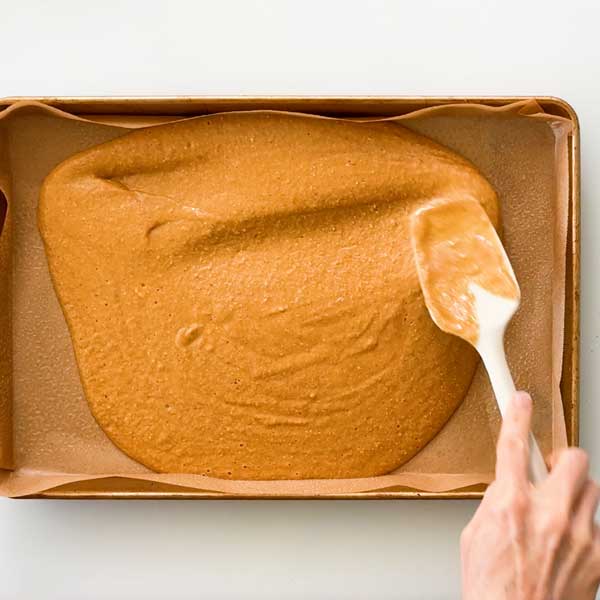 Spreading the cake batter in a jelly roll plan lined with parchment paper.