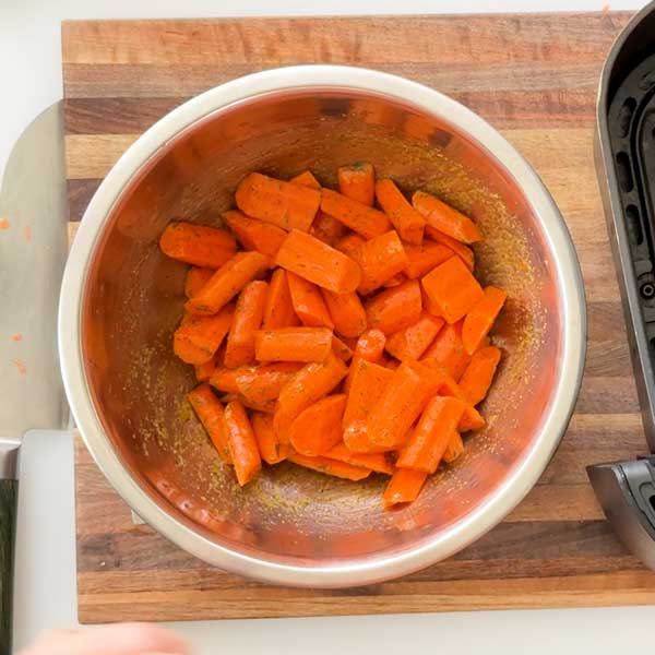Add carrots to the bowl and toss in the maple syrup and oil.